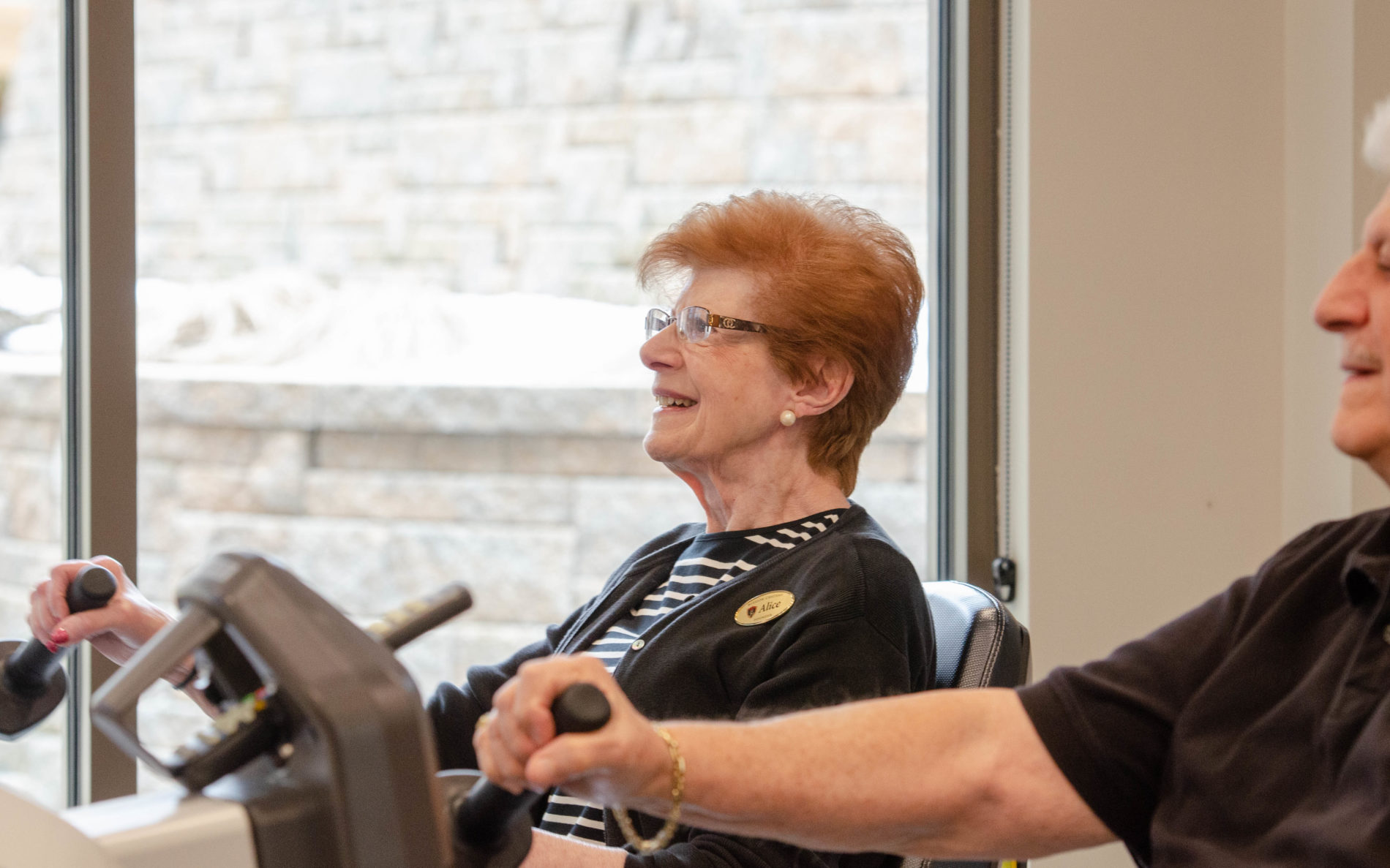 A resident enjoying the fitness area as she smiles while on a workout machine