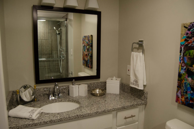 Bathroom sink with decorative towels and a large square mirror above the facet