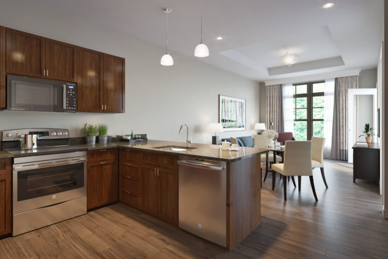 furnished kitchen with silver appliances and clean countertops , a dining room table is in the background