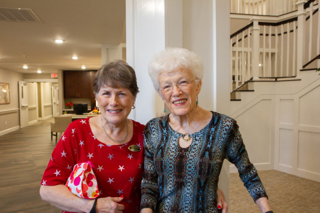 Two female resident friends smiling at the camera with their arms around each other.