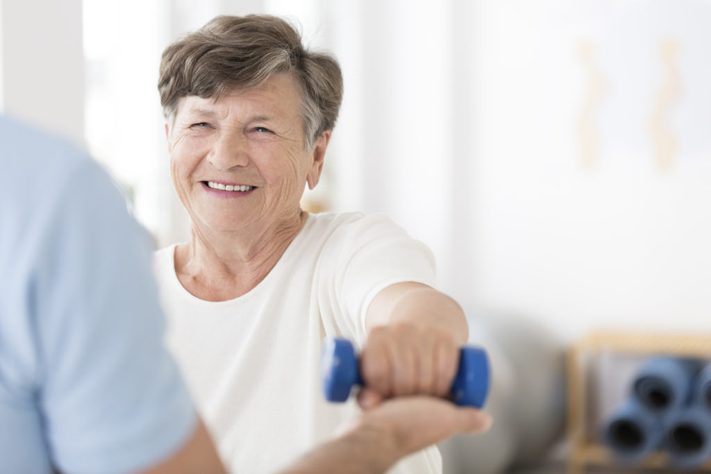 senior woman exercising with physical therapist