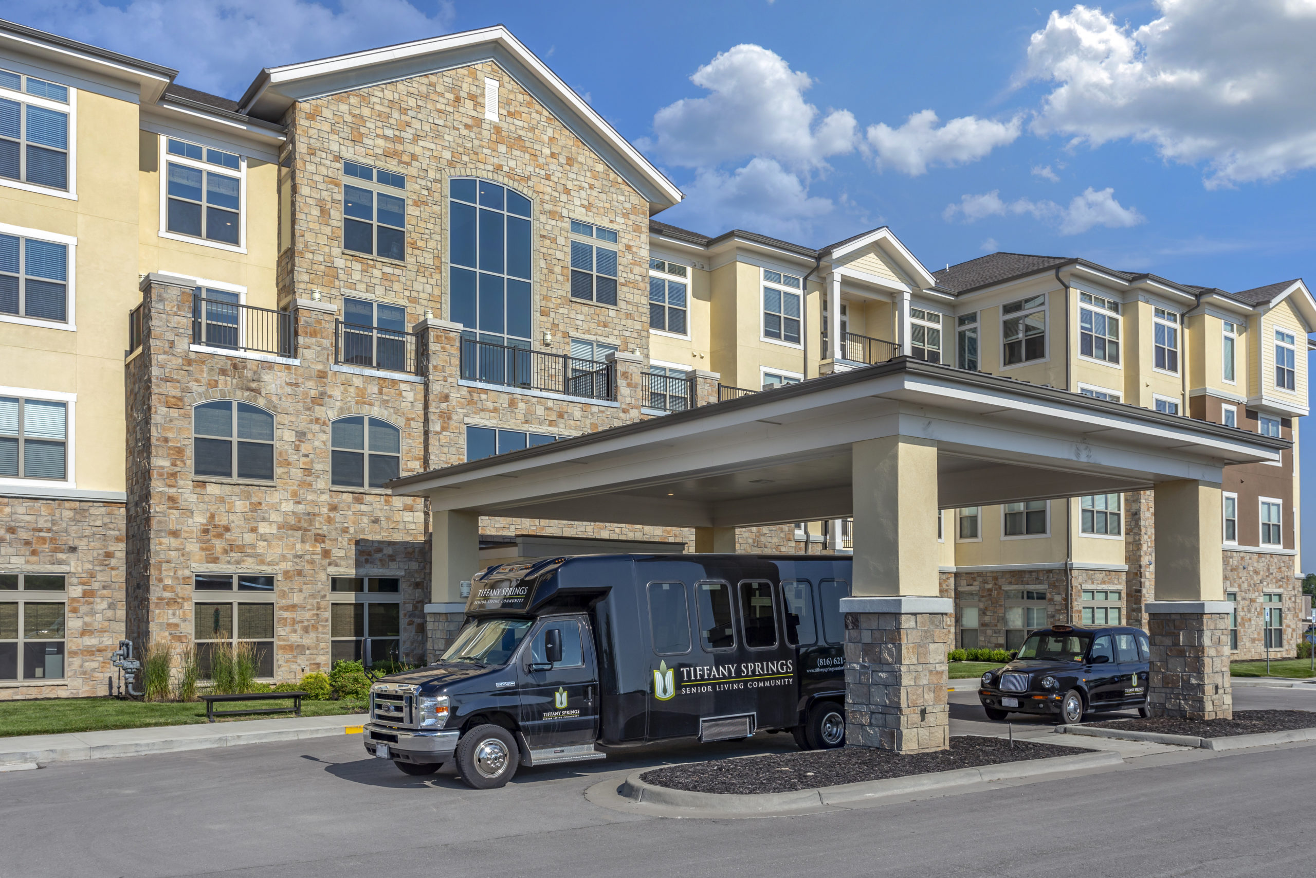 Tiffany Springs Senior Living exterior with transportation vehicles parked in front