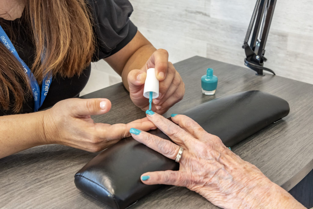 Woman painting elderly nails blue